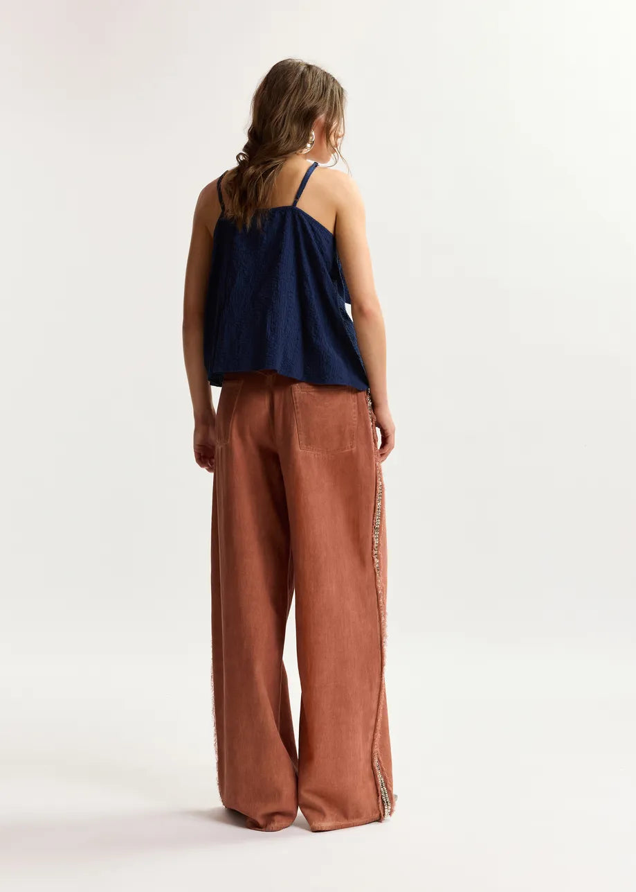 Woman wearing a navy top and brown pants on a white background