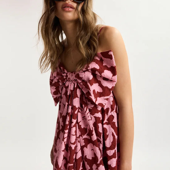 Woman wearing a pink floral dress and sunglasses on a white background