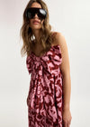 Woman wearing a pink floral dress and sunglasses on a white background