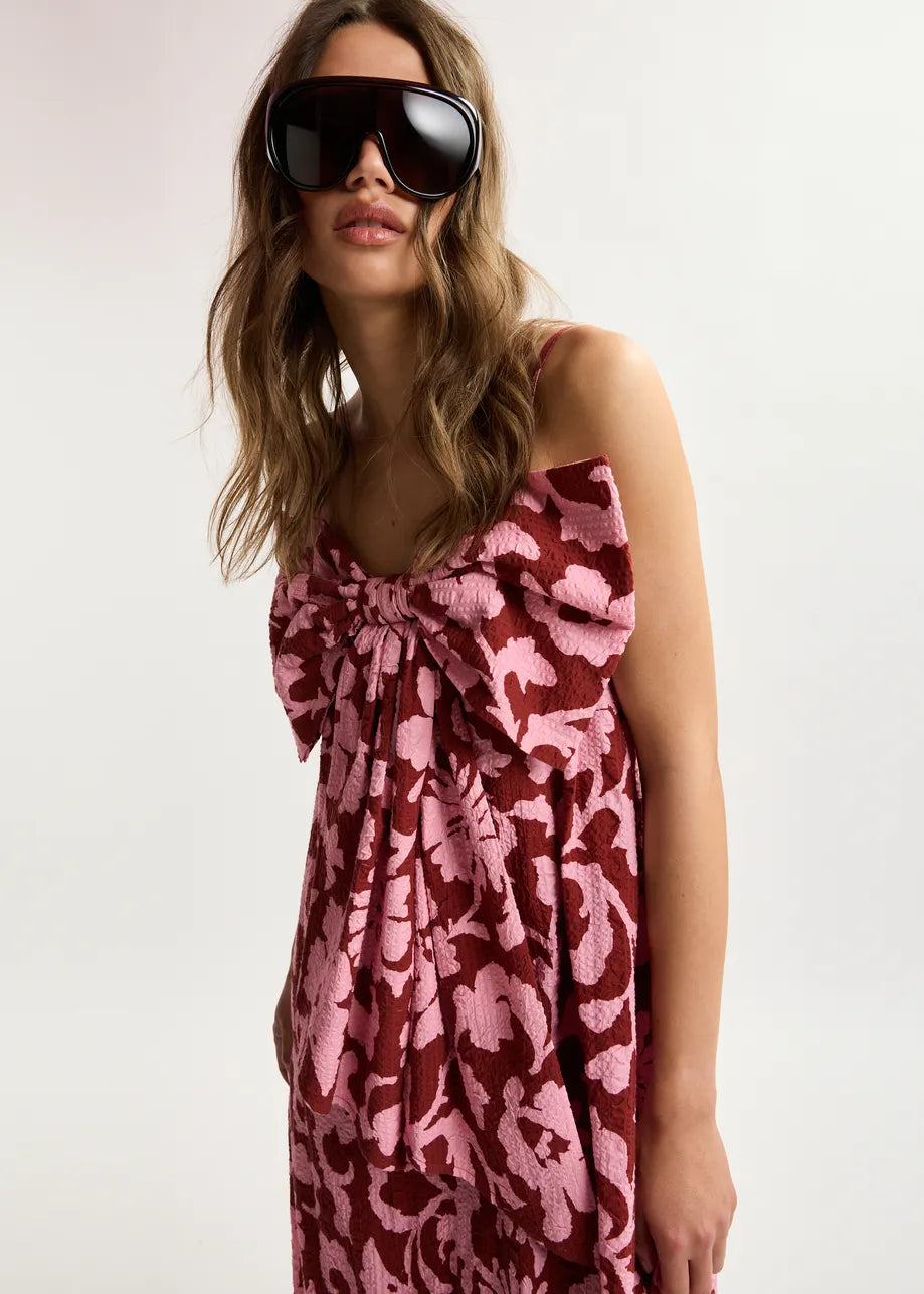 Woman wearing a pink floral dress and sunglasses on a white background