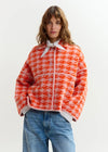 houndstooth red textured jacket with pink background  model