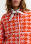 houndstooth red textured jacket with pink background  close up