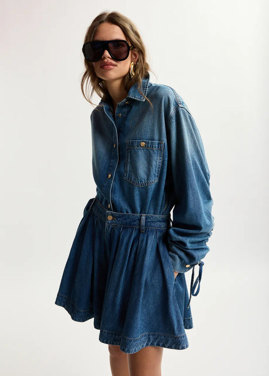 Woman wearing a blue denim dress with sunglasses on a white background