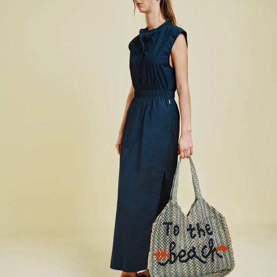 woman carrying blue and beige string bag on green background