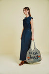 woman carrying blue and beige string bag on green background