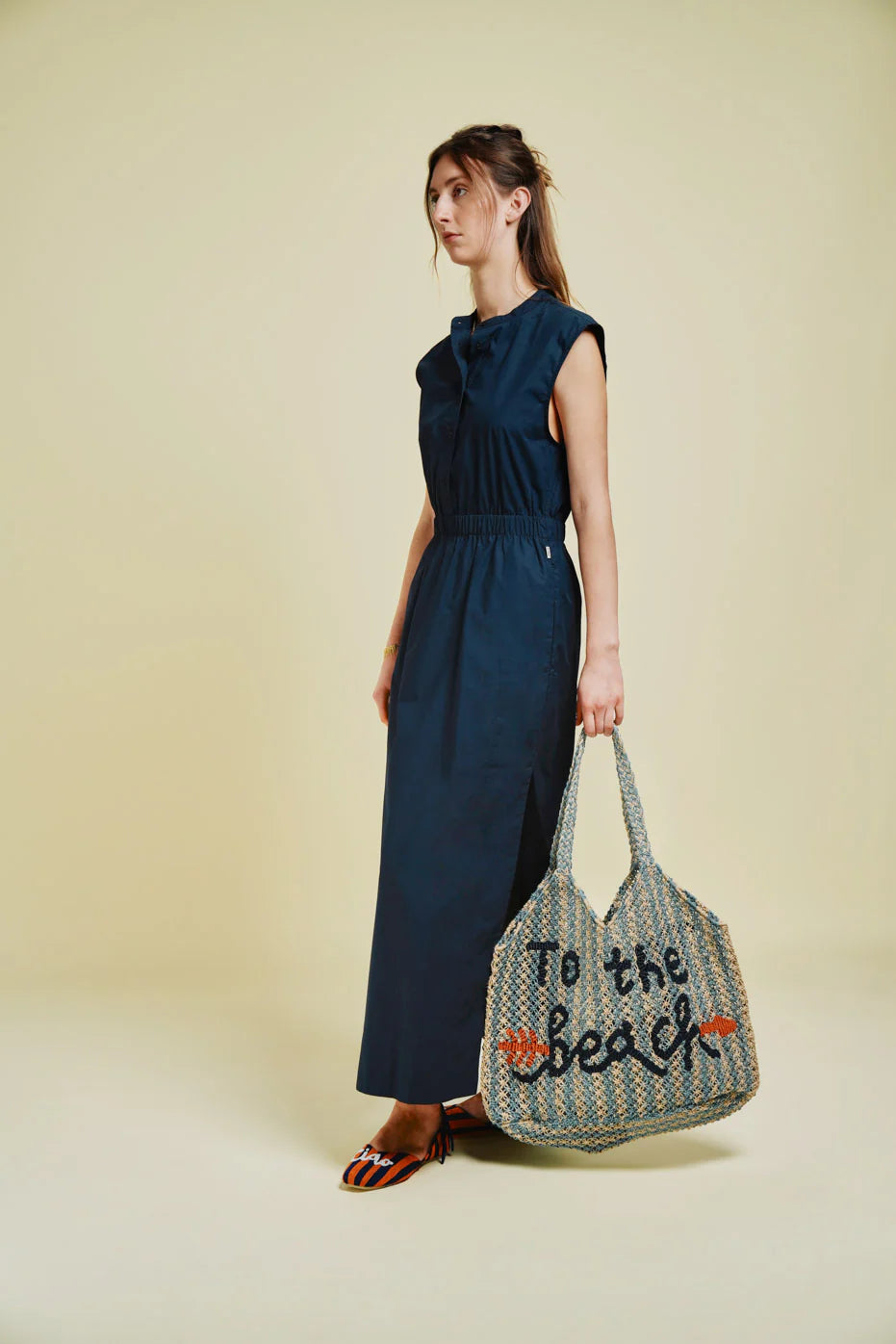 woman carrying blue and beige string bag on green background