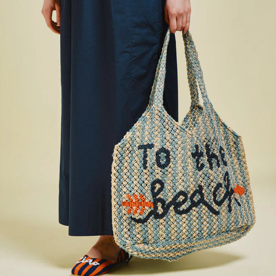 blue and beige string bag on green background in someones hand