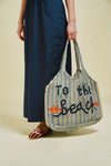blue and beige string bag on green background in someones hand
