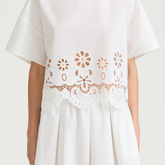 White top with floral lace details on a plain background