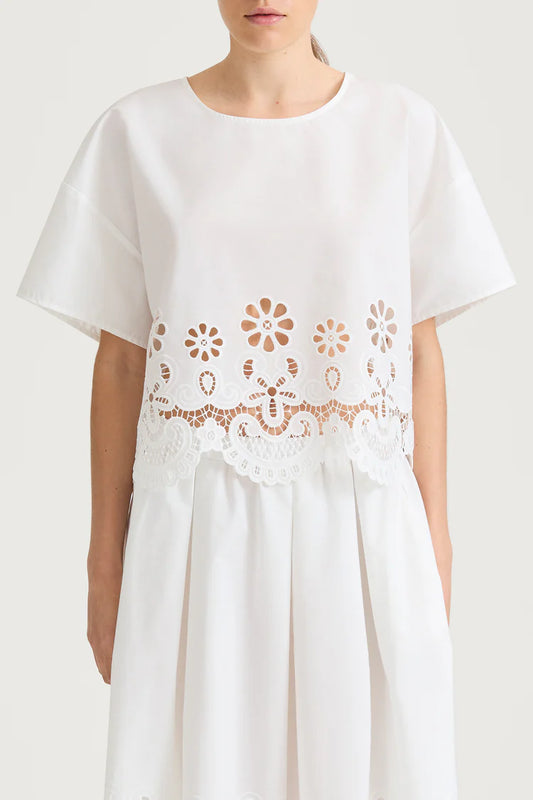 White top with floral lace details on a plain background