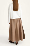 Person wearing a white top and brown skirt on a white background