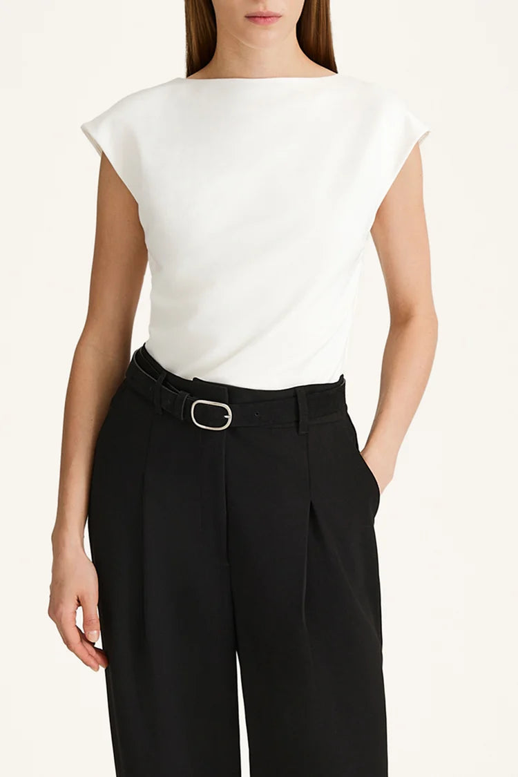 Person wearing a white sleeveless top and black pants on a plain background