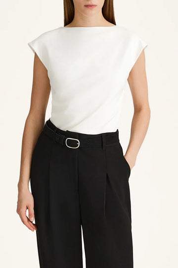 Person wearing a white sleeveless top and black pants on a plain background