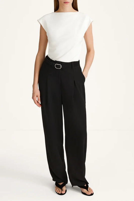 A model wearing black wide-leg trousers with a matching black belt and silver buckle, paired with a white sleeveless top and black sandals, against a plain white studio background.