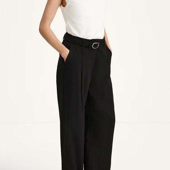 Person wearing a white top and black high-waisted pants on a white background