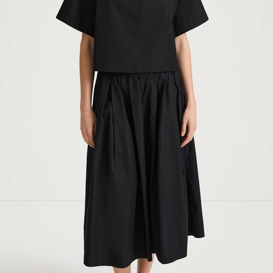 Person wearing a black outfit with a top and skirt on a white background from Stylin