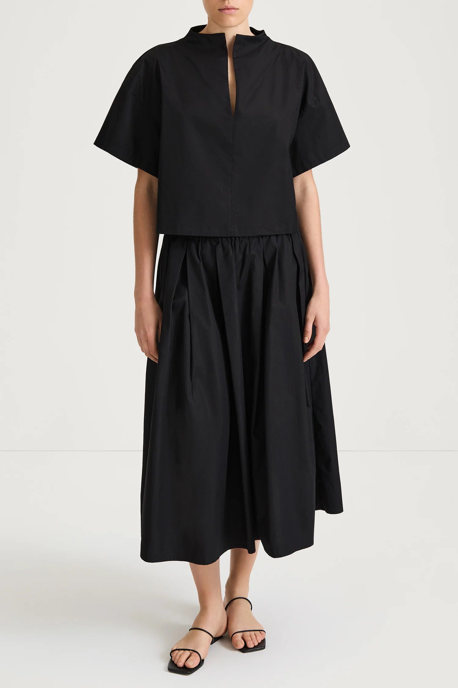 Person wearing a black outfit with a top and skirt on a white background from Stylin