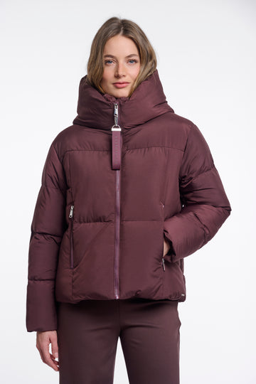 Woman wearing a maroon puffer jacket on a white background