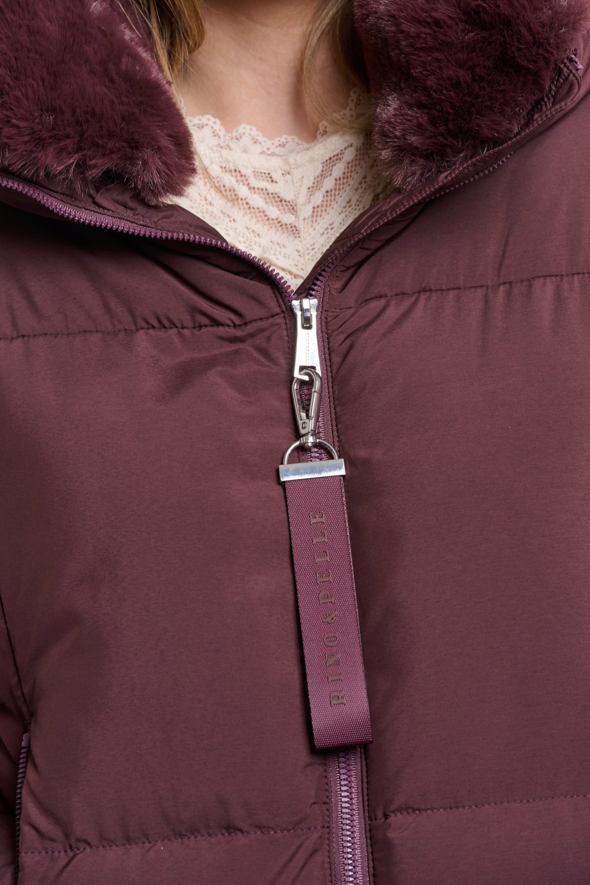 Close-up of a purple puffer jacket with fur hood and zipper detail.