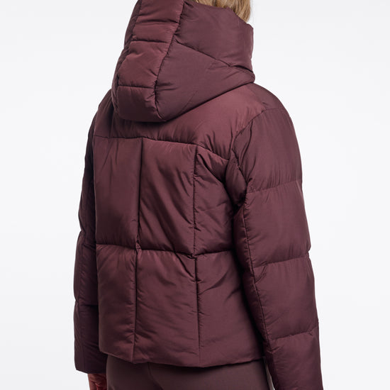 Person wearing a maroon puffer jacket on a white background