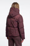 Person wearing a maroon puffer jacket on a white background