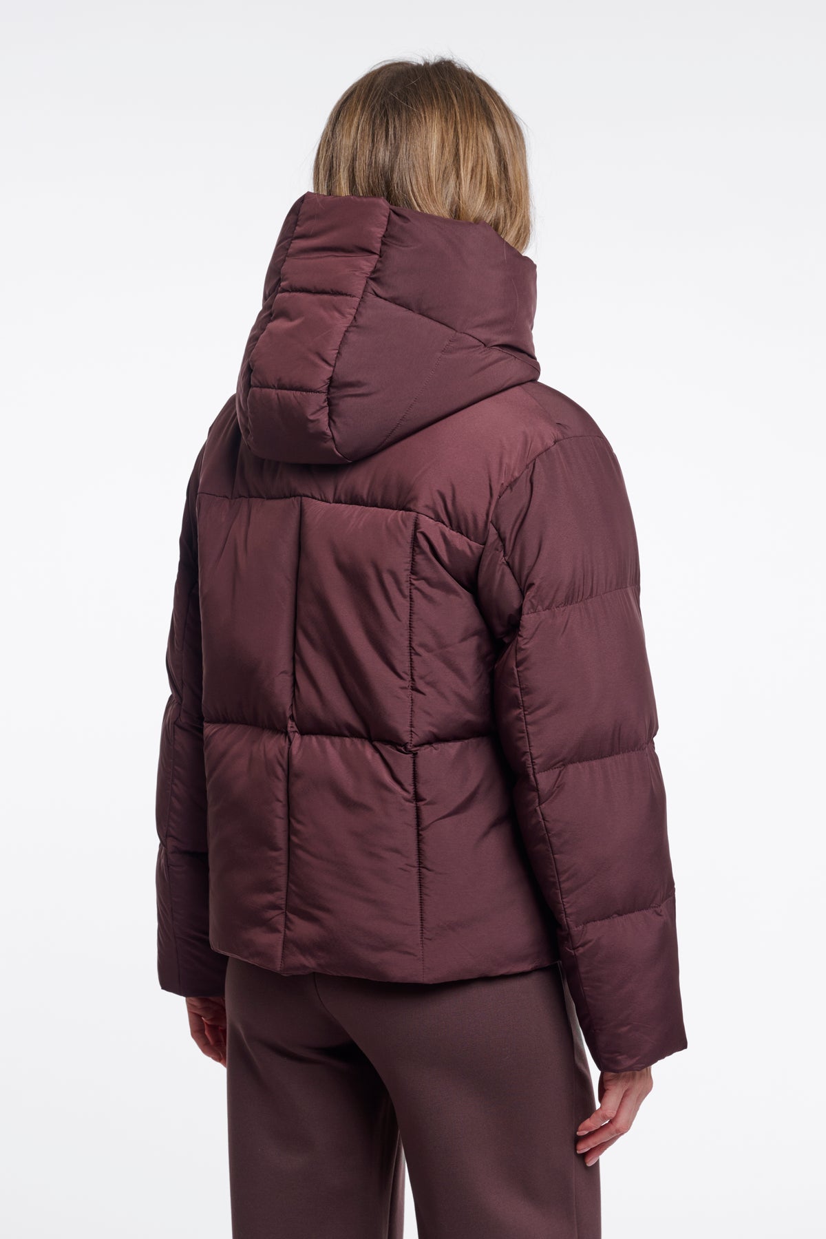 Person wearing a maroon puffer jacket on a white background