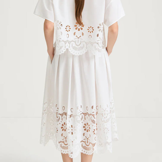 White top and skirt with floral lace details on a white background