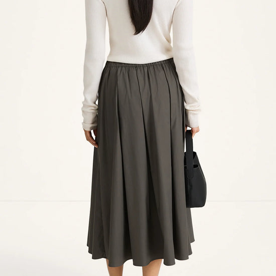 woman wearing grey skirt and white long sleeve top on white background