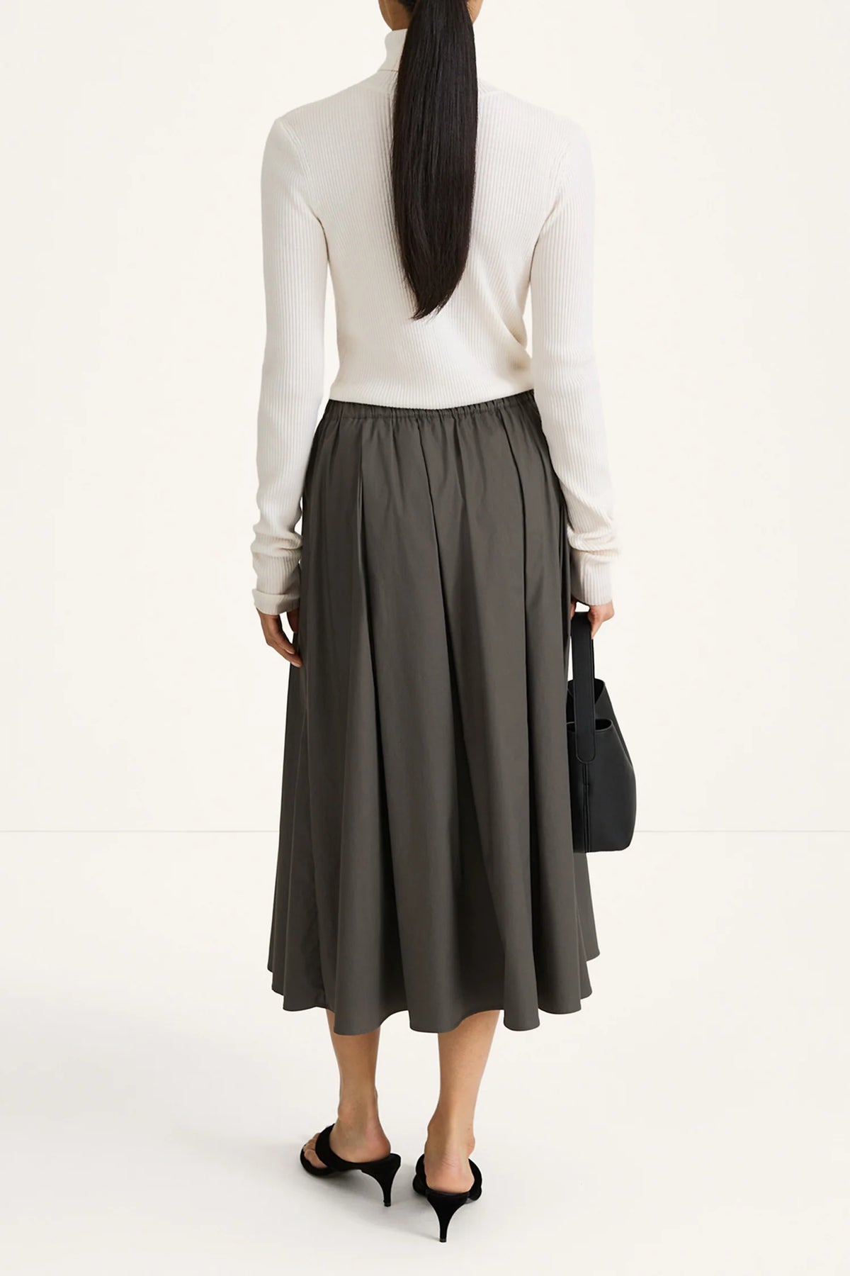 woman wearing grey skirt and white long sleeve top on white background