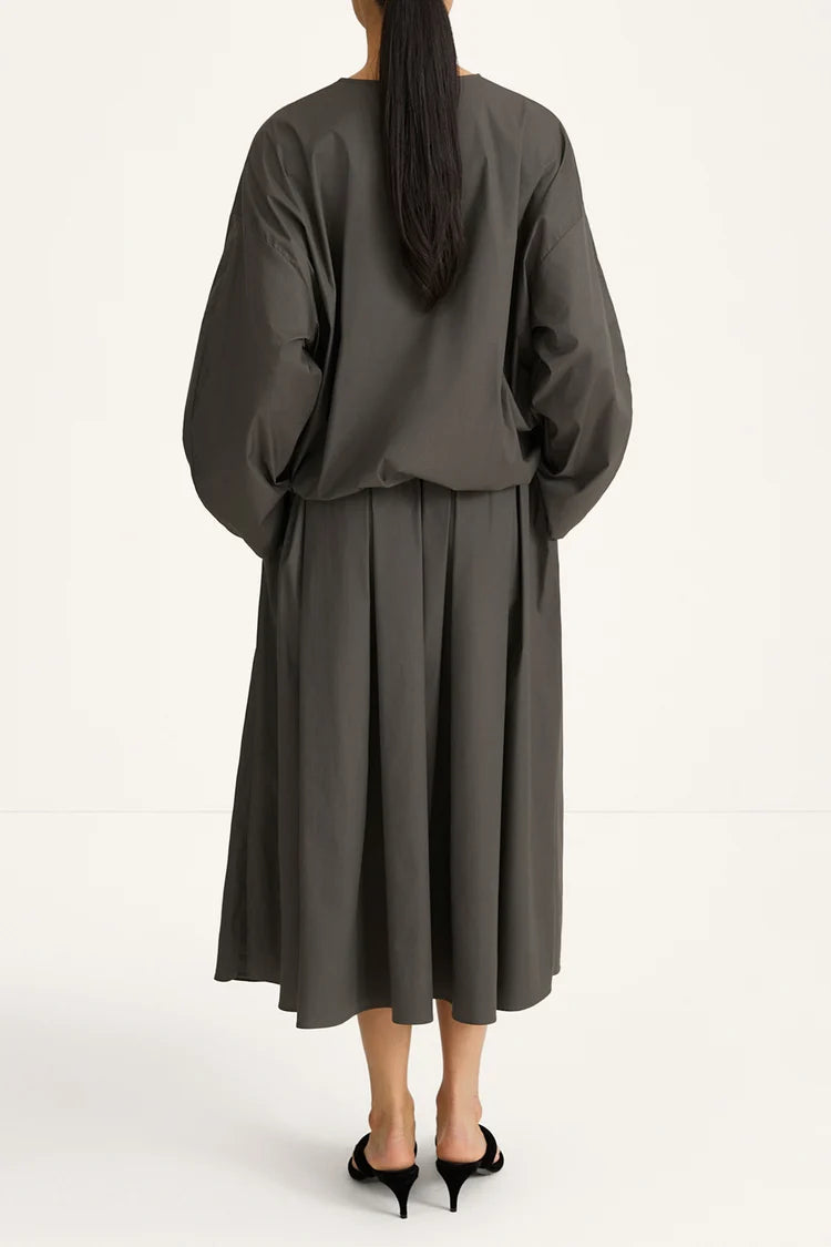 woman wearing a grey blouse and skirt on a white background rear view