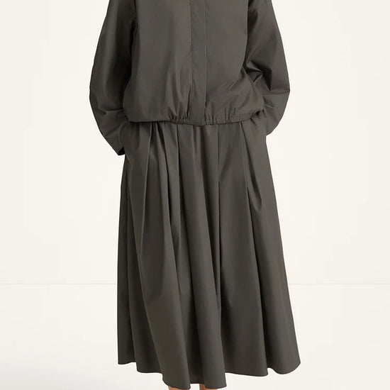 woman wearing a grey blouse and skirt and back heels on a white background 