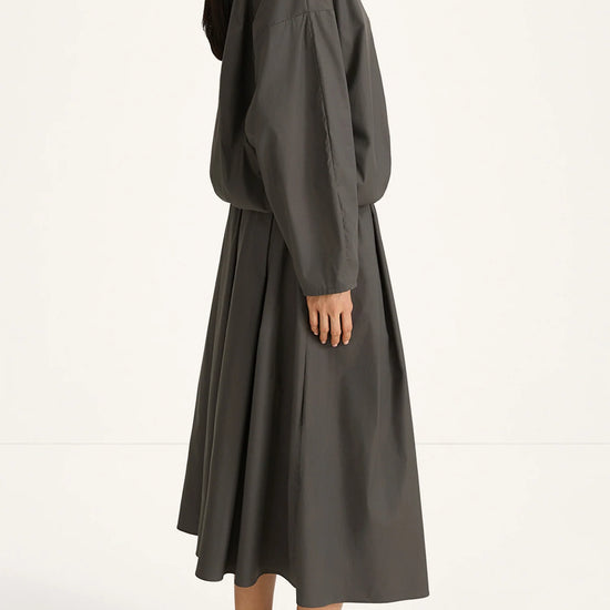 woman wearing a grey blouse and skirt on a white background side view