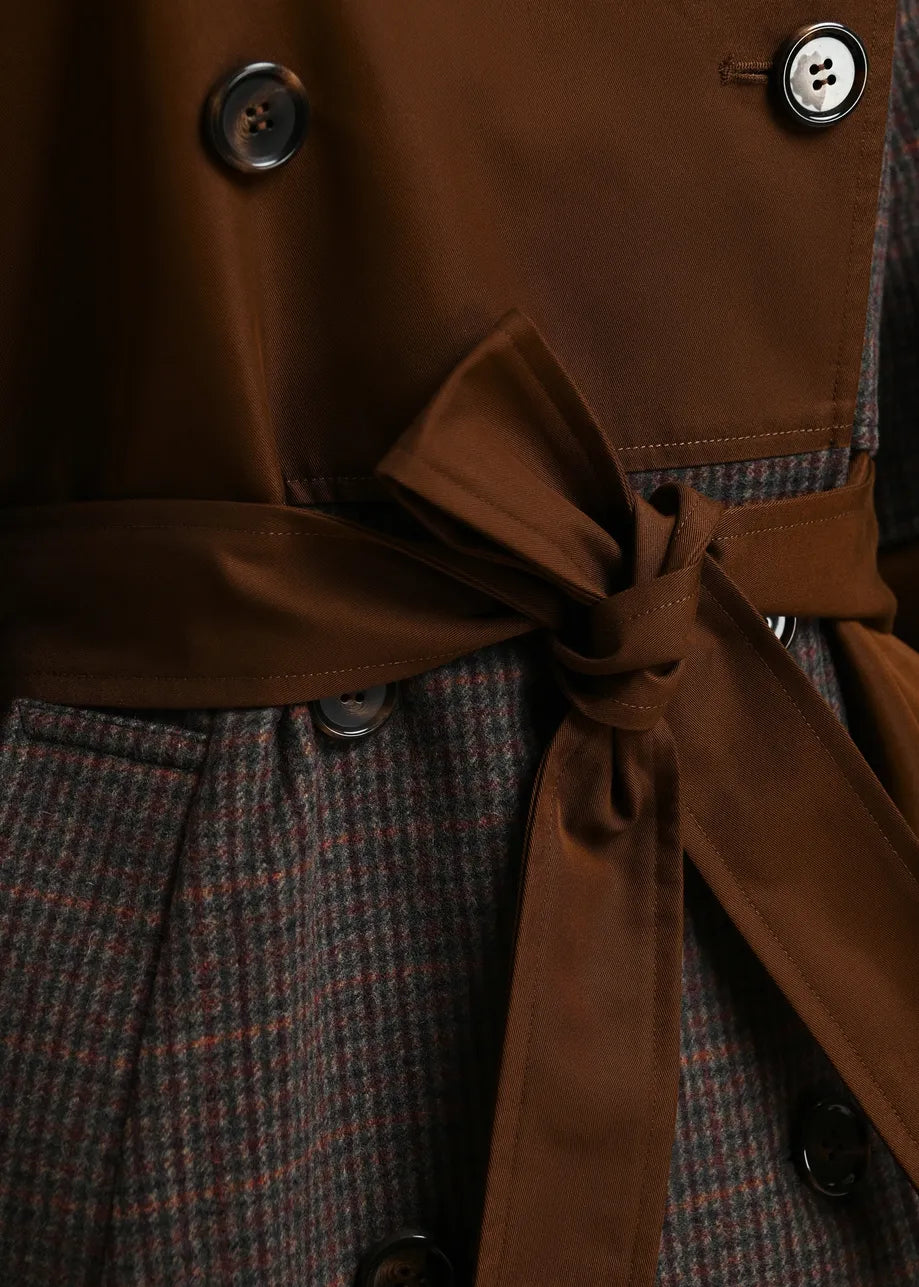 Close-up of a double-breasted coat with a brown satin-like waist tie and a brown-and-gray houndstooth patterned body, showing dark buttons.