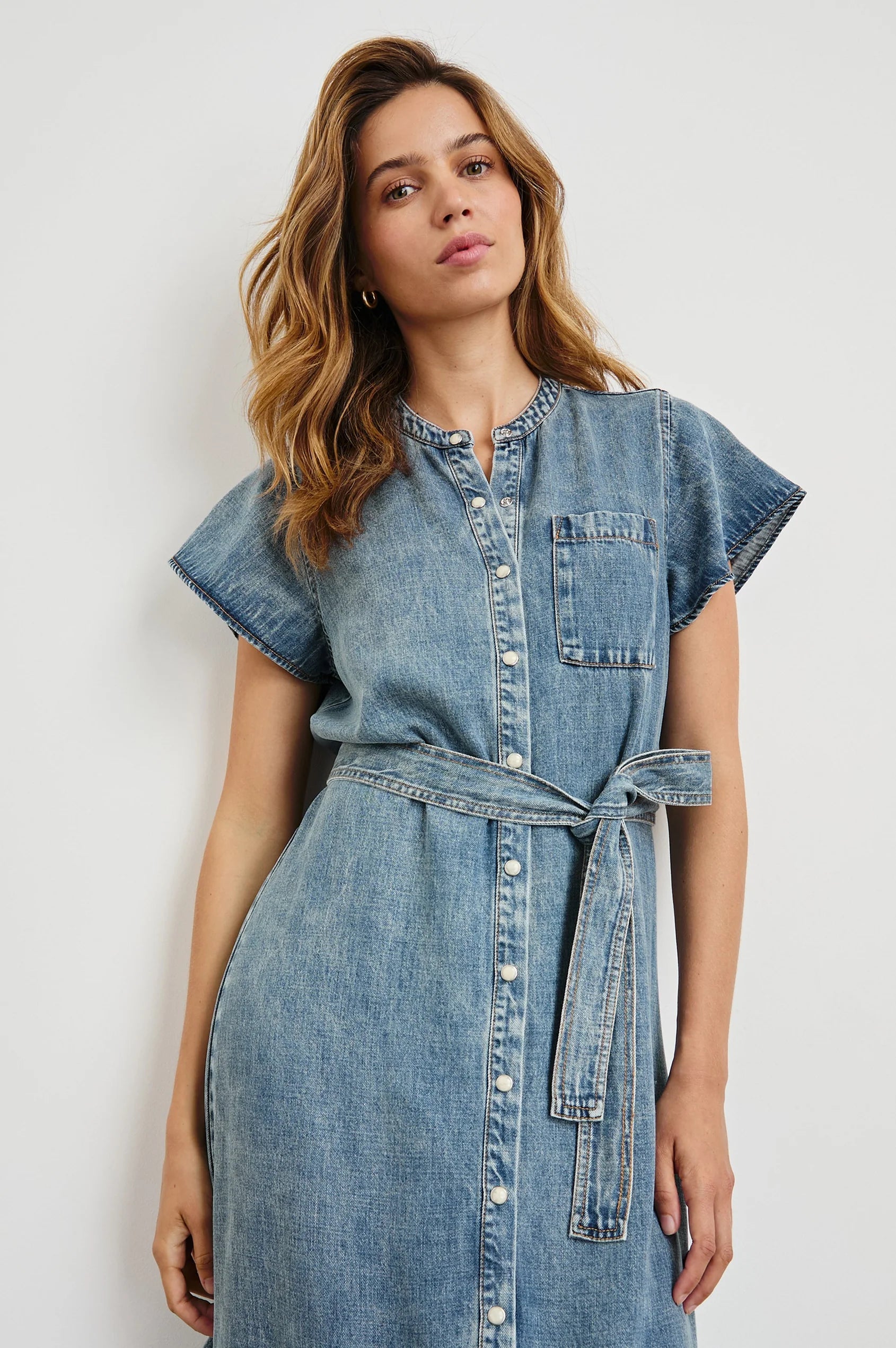 Woman wearing a denim dress against a white background