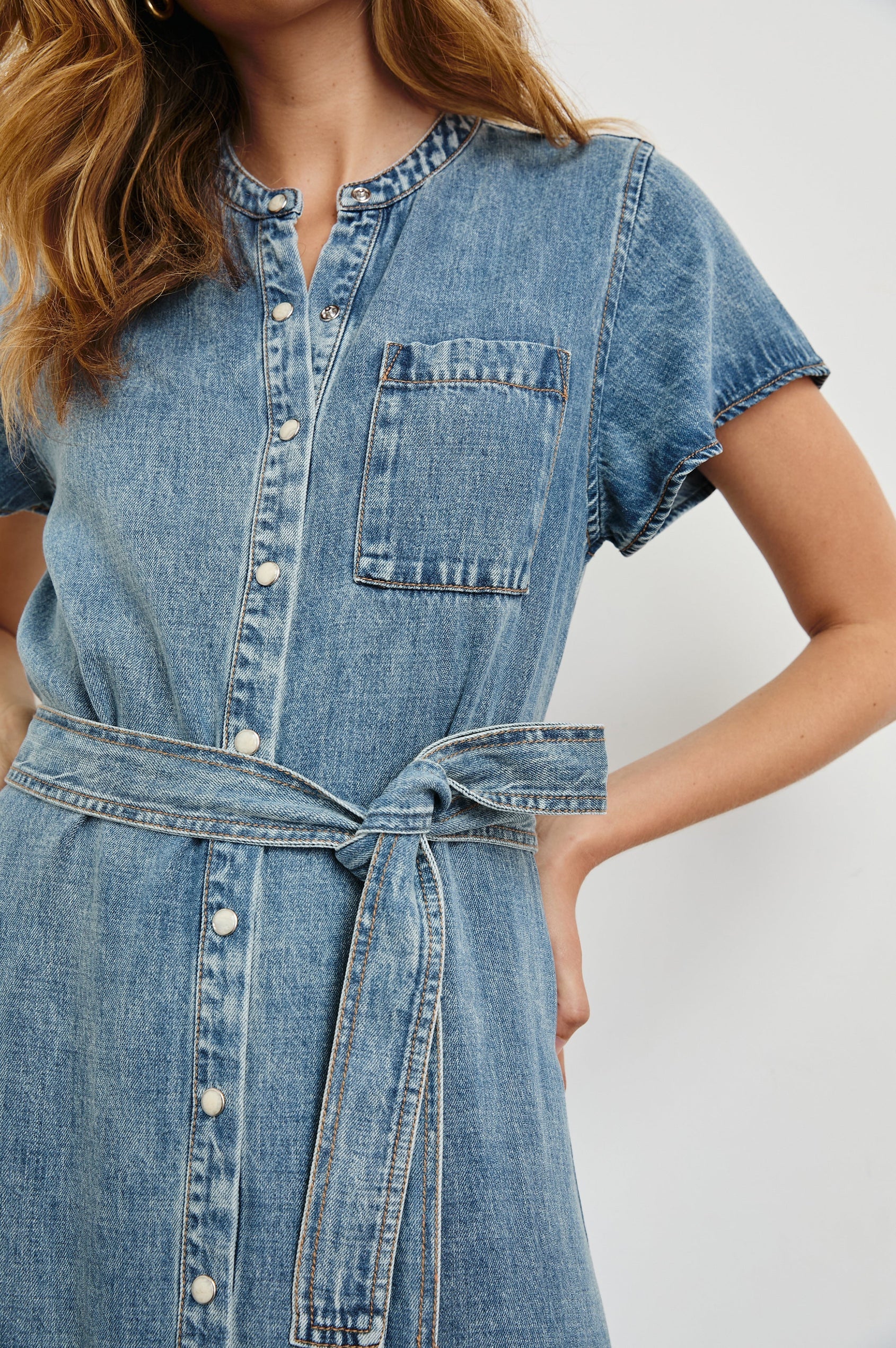 Denim dress with a belt on a plain background