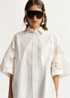 Woman wearing a white shirt with lace sleeves against a white background