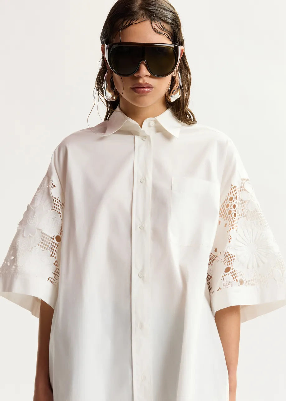 Woman wearing a white shirt with lace sleeves against a white background
