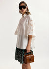 model wearing white lace shirt on plain background