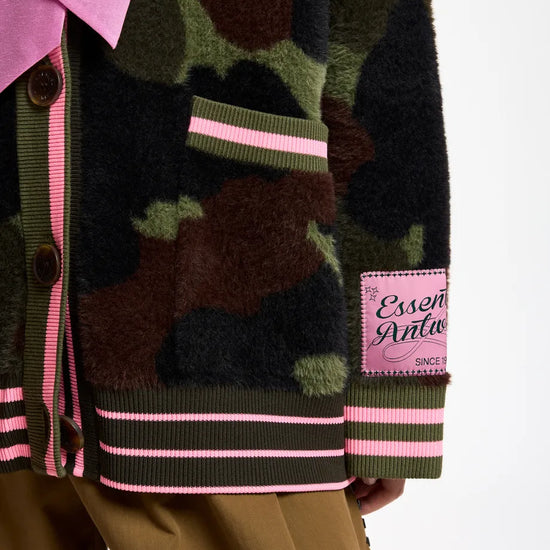 Close-up of a fuzzy camouflage cardigan with pink striped trim and a pink brand patch 