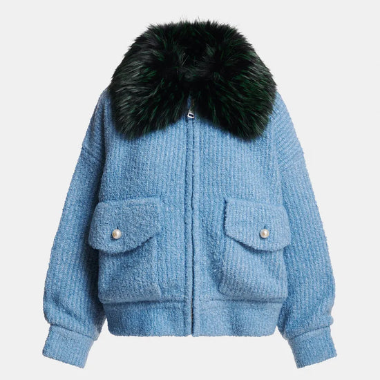 A light blue textured bouclé jacket with a large black fur collar, featuring two front flap pockets with silver-tone snap buttons, shown against a plain light gray background.