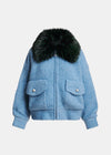 A light blue textured bouclé jacket with a large black fur collar, featuring two front flap pockets with silver-tone snap buttons, shown against a plain light gray background.