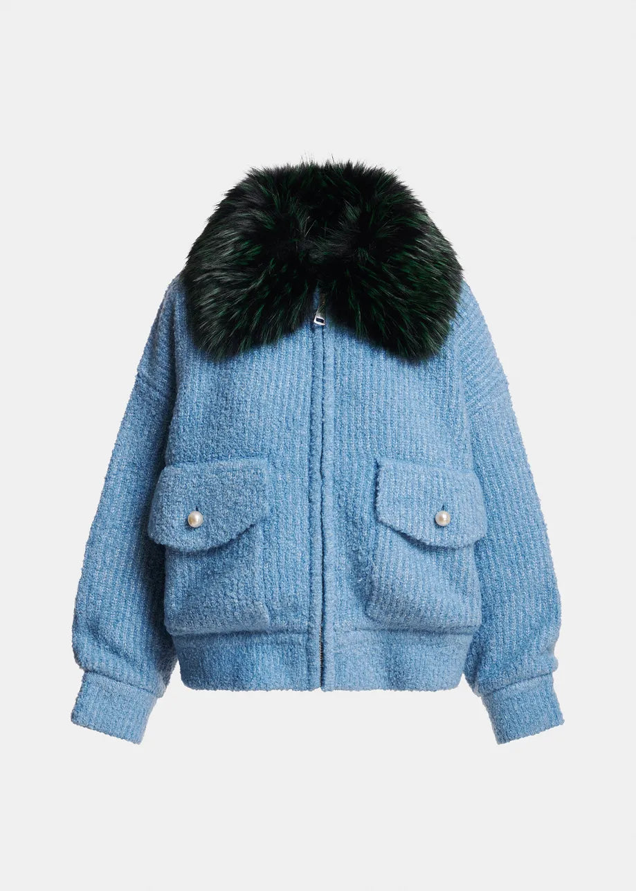 A light blue textured bouclé jacket with a large black fur collar, featuring two front flap pockets with silver-tone snap buttons, shown against a plain light gray background.