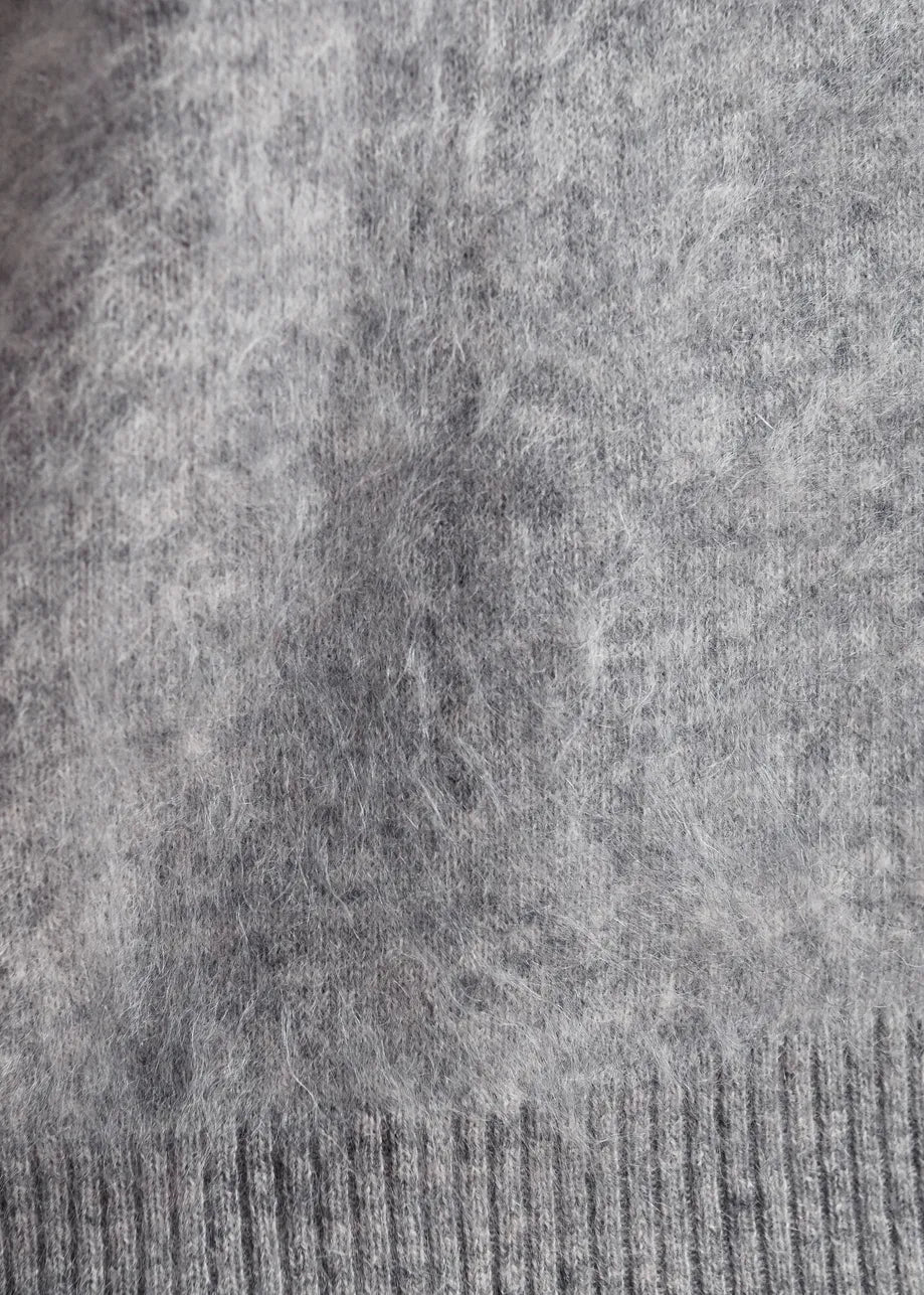 Close-up of a gray knit fabric with a ribbed cuff at the bottom.