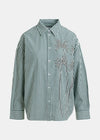 Green and white striped shirt with floral embroidery on a light gray background