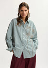 Model wearing a green stripe shirt with embellishment 