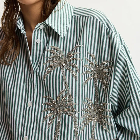 Green and white striped shirt with silver sequin palm tree design on a plain background