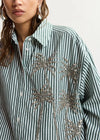 Green and white striped shirt with silver sequin palm tree design on a plain background