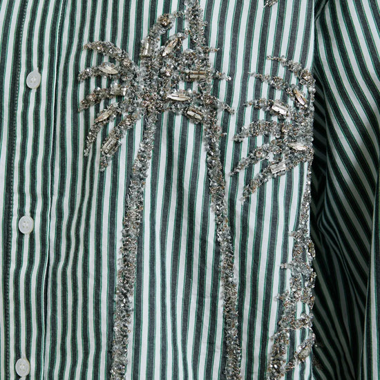Close-up of a green and white striped shirt with decorative embellishments.