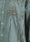 Close-up of a green and white striped shirt with decorative embellishments.