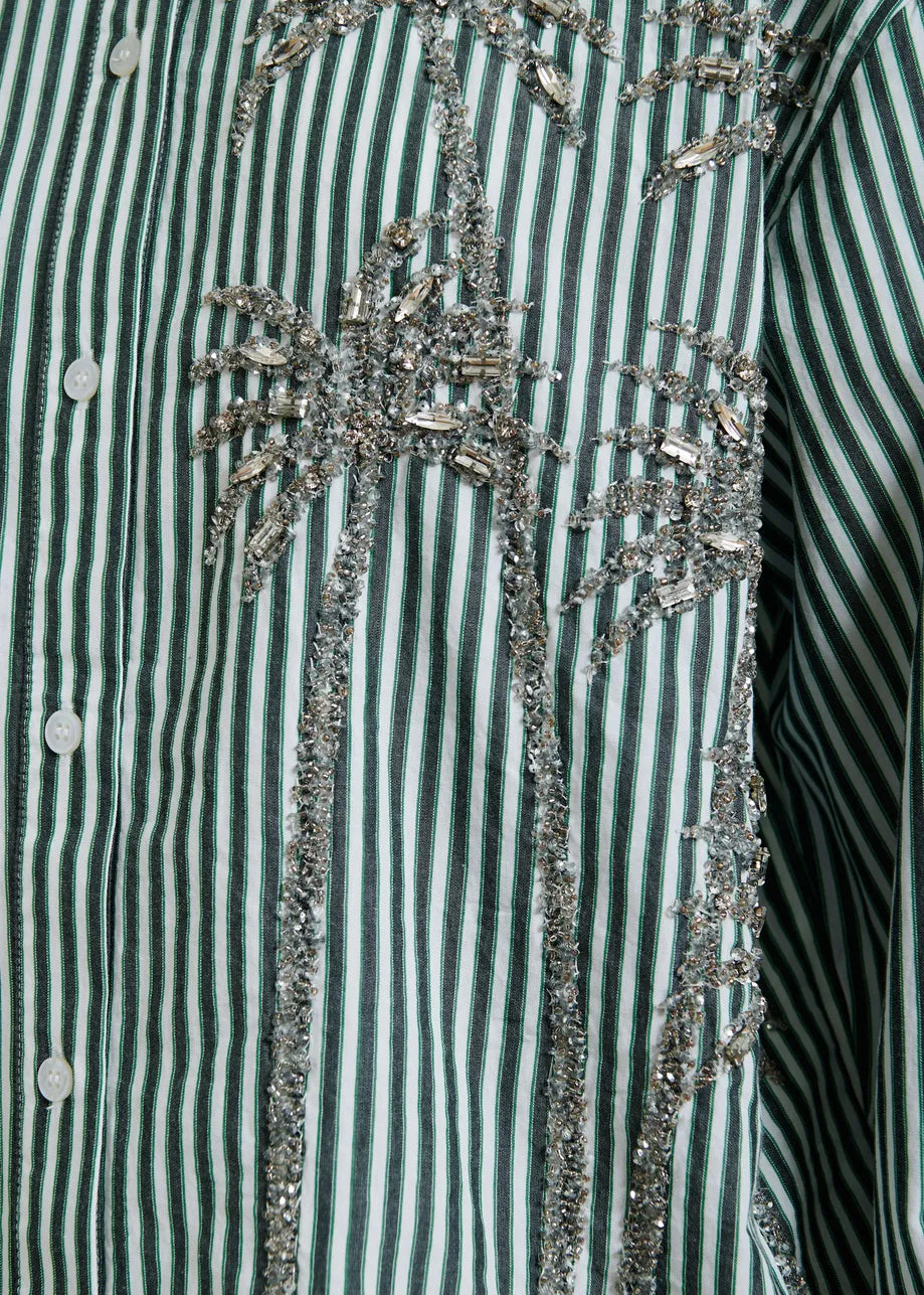Close-up of a green and white striped shirt with decorative embellishments.